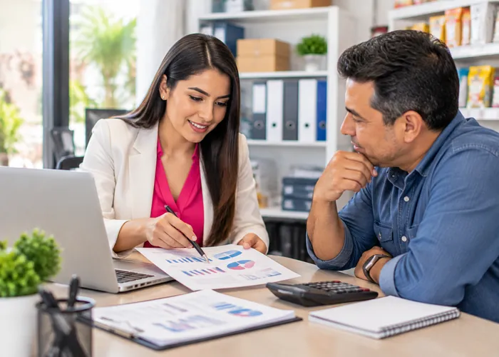 Contadora atendiendo a un cliente en una reunión con informes y calculadora